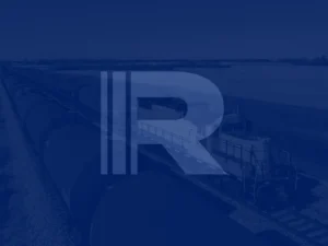 Freight train with tank cars on railroad tracks in a rural area, overlaid with a large stylized "R" and vertical lines.