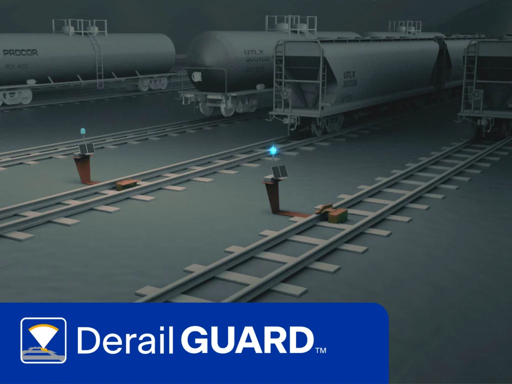 A nighttime rail yard scene shows several freight cars on tracks with derail devices and indicator lights; "DerailGUARD" logo is displayed at the bottom.
